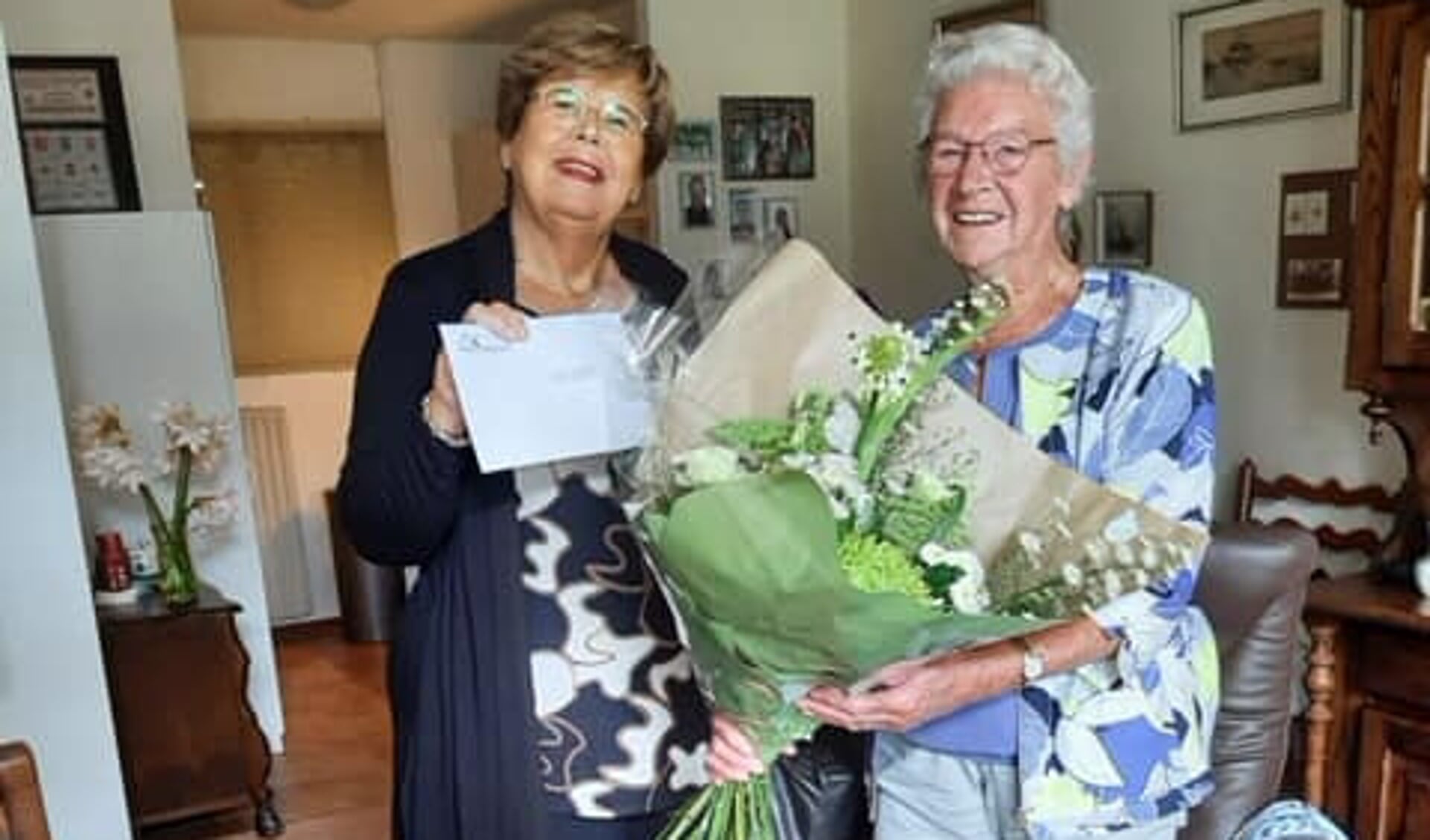 Mevrouw Van Beek straalt als ze een bosje bloemen krijgt van de burgemeester.