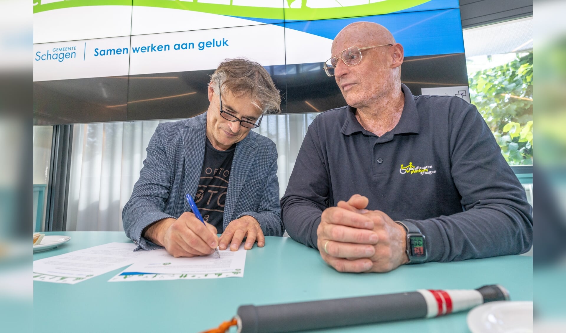 Wethouder Sigge van der Veek en voorzitter van Gehandicaptenplatform Schagen Marcel van Baar, ondertekenen het akkoord. 