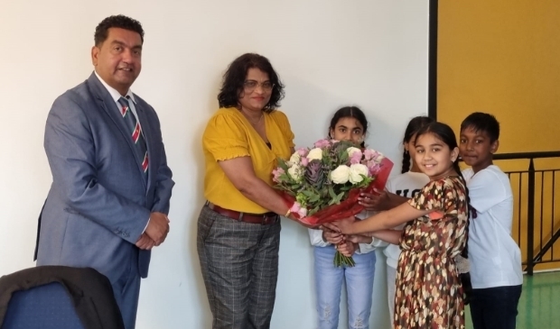 <p>Senrita Gobardhan krijgt een bos bloemen van enkele leerlingen van SVS. Links is Rajesh Ramnewash. </p>