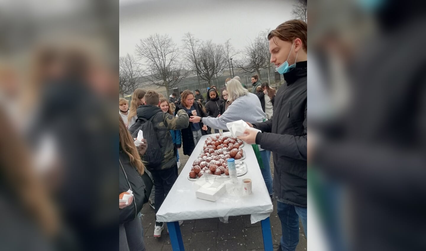 Oliebollen worden uitgedeeld op het schoolplein.