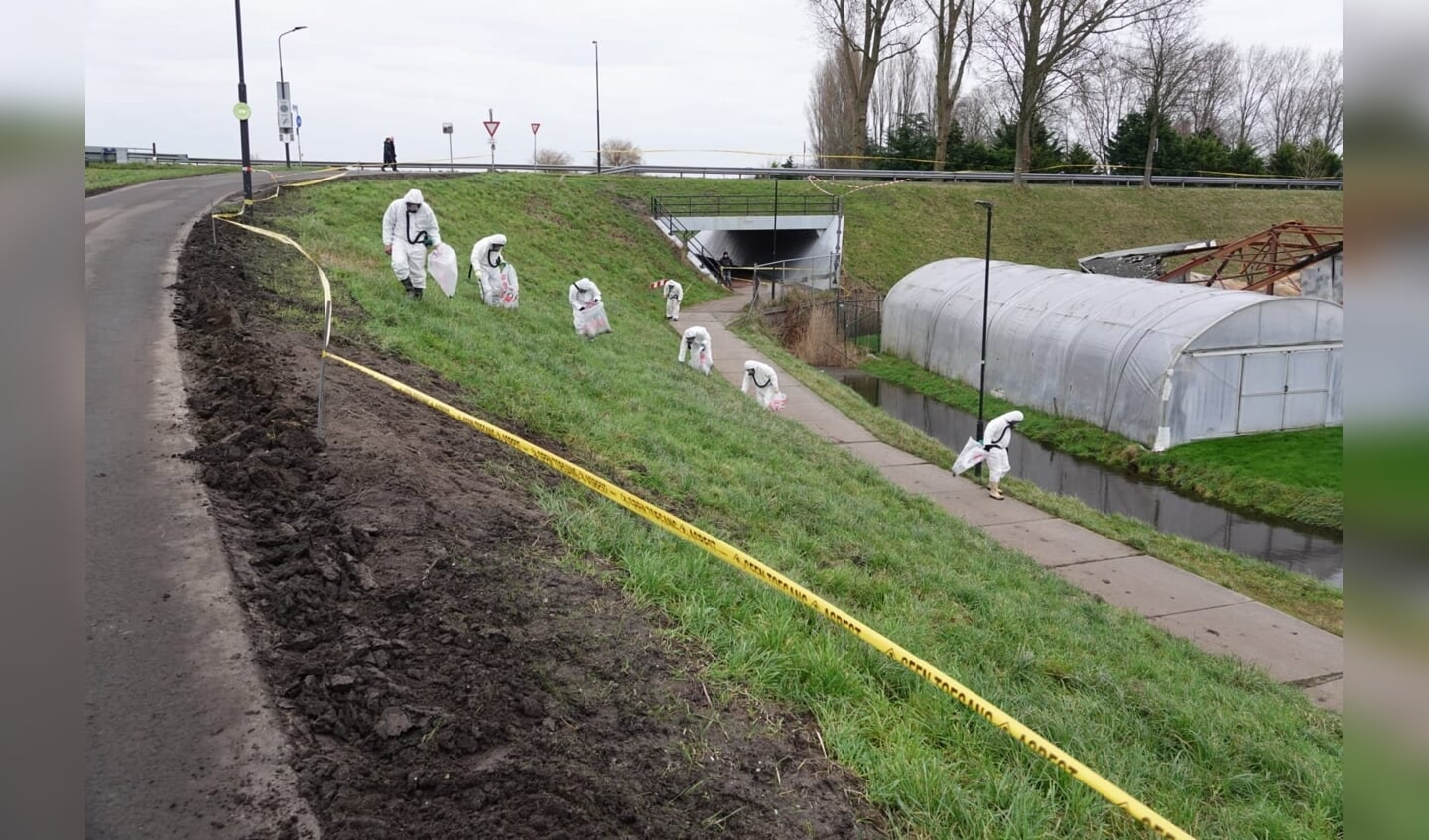 Mensen in speciale beschermingskleding zijn bezig met de verwijdering van asbest.