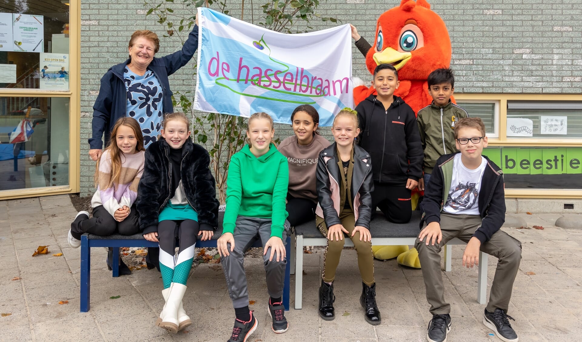 Directeur Janette Kuipers en de leerlingenraad onthulden samen met mascotte Lenny de eerste boom op het schoolplein van De Hasselbraam.