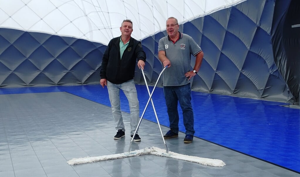 De vloer van de blaashal moet regelmatig geveegd worden. Voorzitter Jan Kees Boot (rechts) en bestuurslid Ed Boender begonnen vrijdag spontaan met de schoonmaak. (Foto: UWM/gsv)