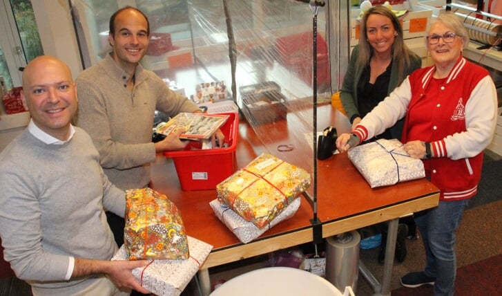 De wethouders (v.l.n.r.) Armand van de Laar, Gijs van Malsen en Larissa Bentvelzen helpen, ingewerkt door Lieke de Reus (rechts), bij Sintvoorieder1 met het inpakken van de cadeautjes voor kinderen in Rijswijk