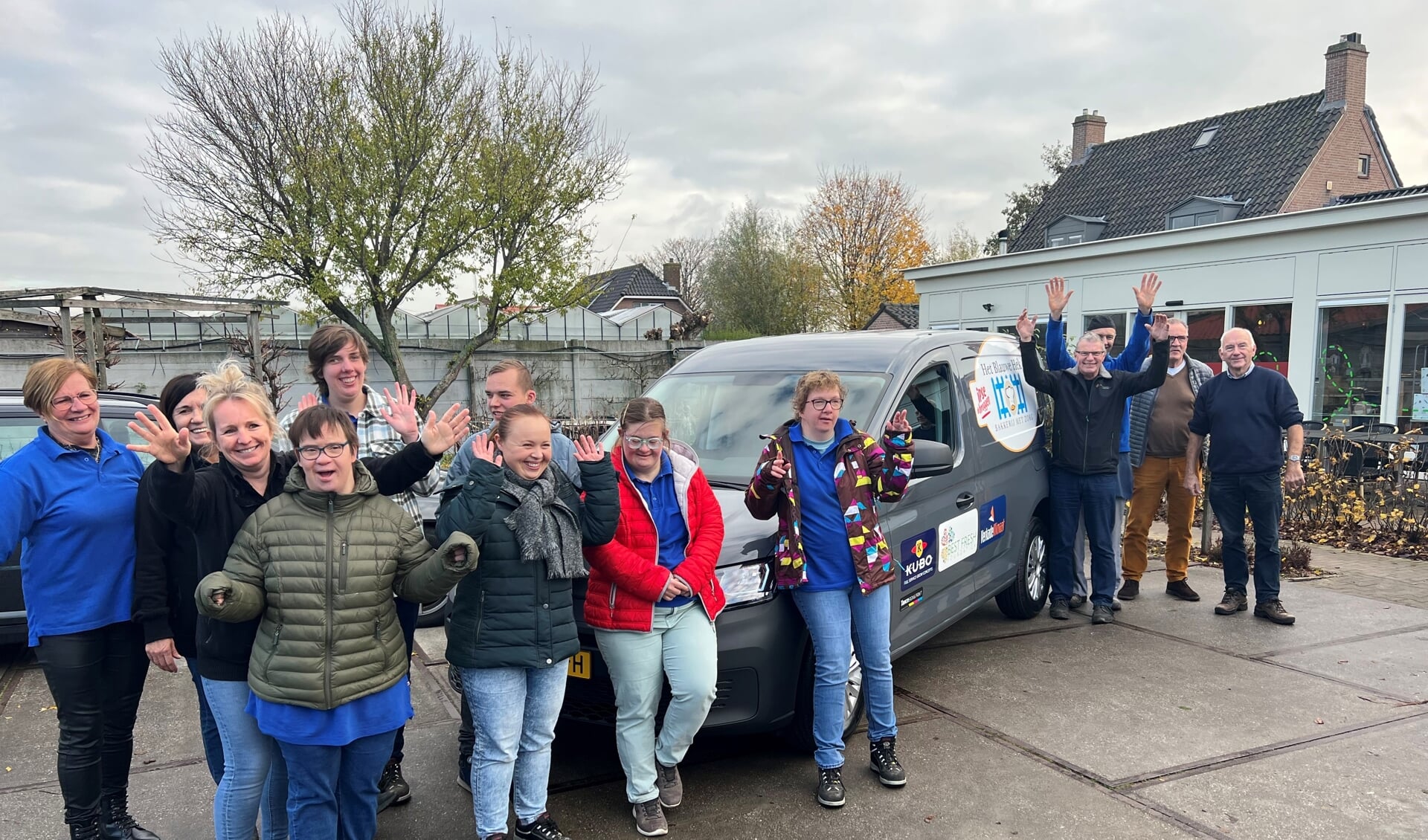 Medewerkers en chauffeurs van Het Blauwe Hek staan trots bij hun nieuwe bestelwagen. 