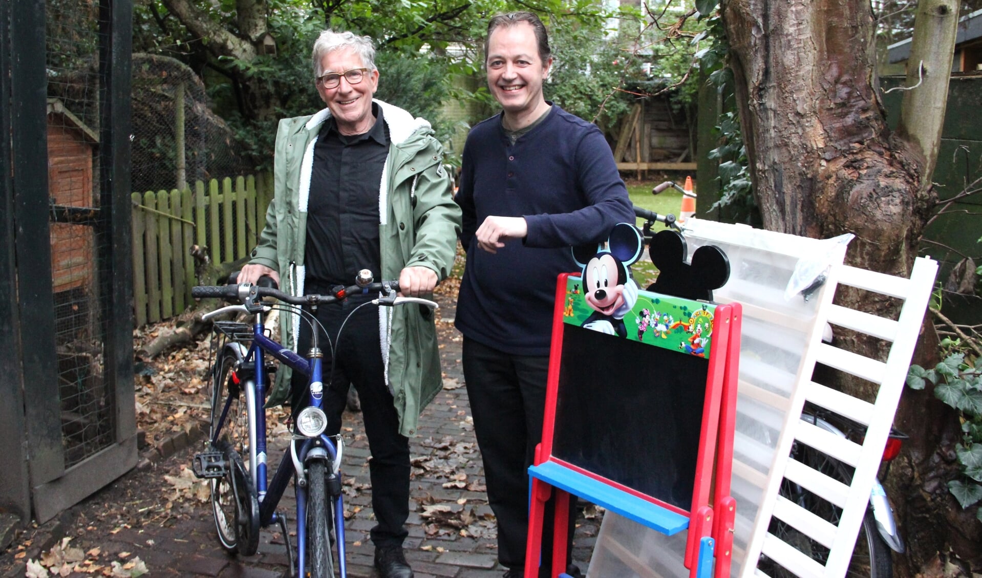 Paul (l) en Wouter bij een fiets, een kinderbedje en een schoolbord. Klaar om weg te brengen.