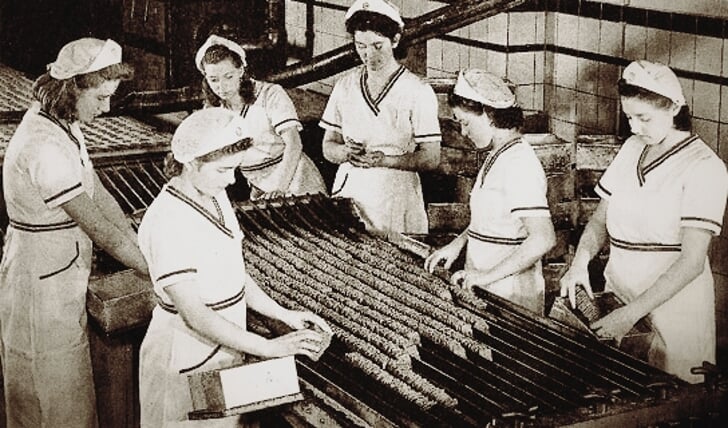Langs een lange band zaten een tiental dames in een hoog tempo de koekjes te rapen en in doosjes doen.  