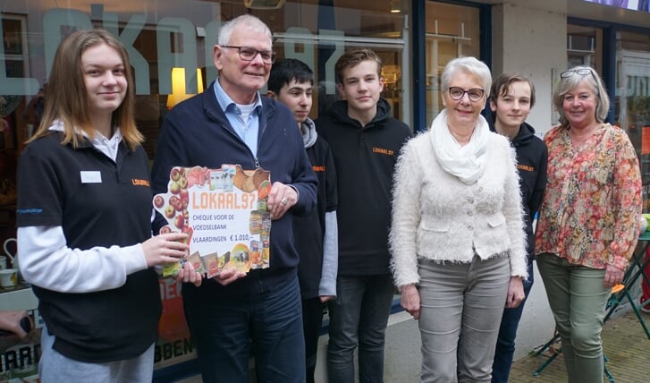 Leo van Houwelingen, voorzitter van de voedselbank, ontvangt van Amy Visser de cheque van 1010 euro, geld dat bijeen is gebracht door de verkoop van tweedehands spullen in de leerwinkel Lokaal97 op de Hoogstraat. Foto: Peter Spek
