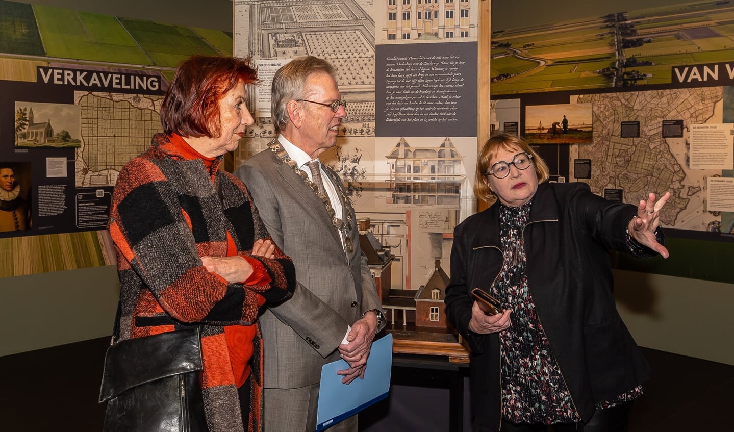 Conservator Saskia van den Berg geeft burgemeester Don Bijl en zijn vrouw een tour door de expositie. 