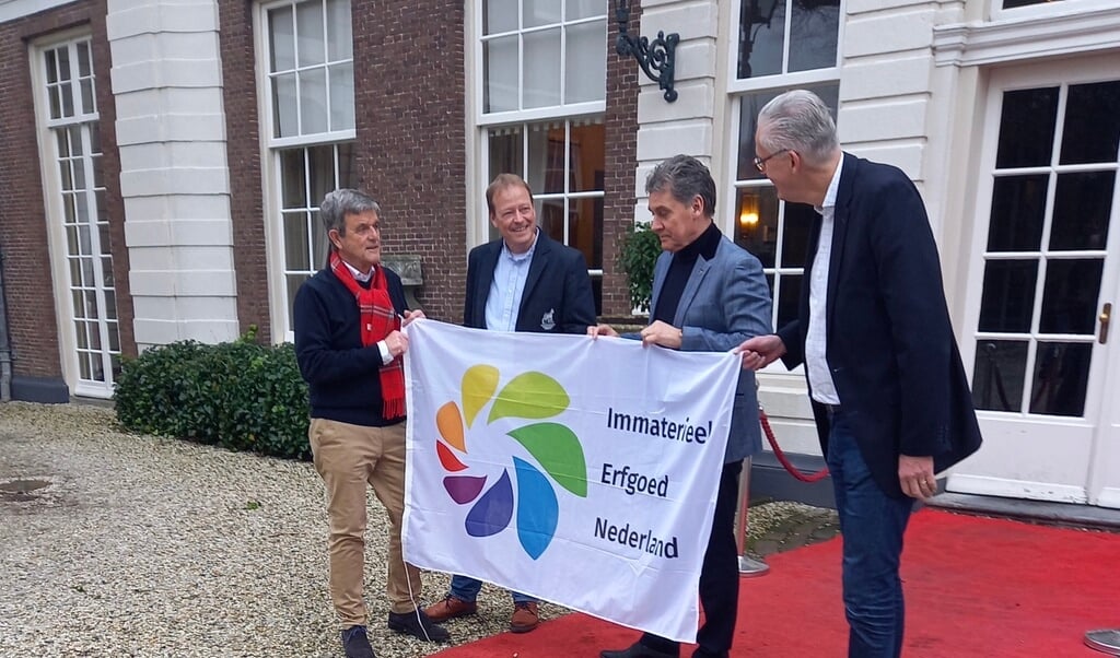 Vlnr: Hans Nelissen, Gerard Post Uiterweer (bestuursleden Harddraverijvereniging) overhandigen de Erfgoedvlag aan wethouders Aad Schoorl en Frits Brouwer 