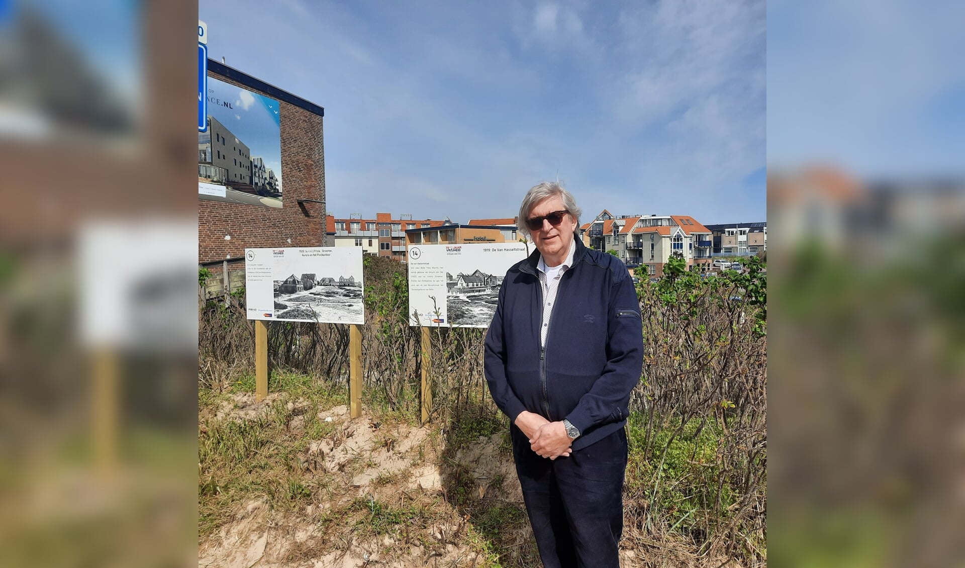 Jaap Stroomer bij enkele panelen van de fotoroute door het hele dorp. Op de achtergrond nog net hotel Prins Maurits te zien 