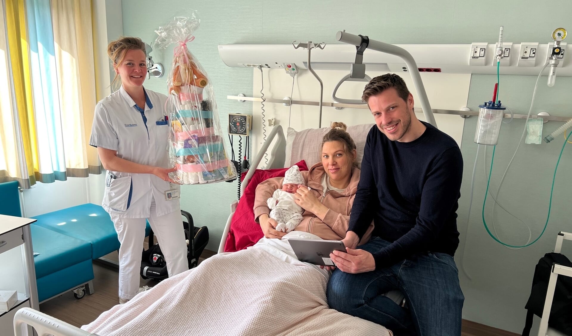 Verpleegkundige Demelza feliciteert de ouders van Livia in het BovenIJ met de geboorte van hun dochter. Marieke en Max regelen vanuit het ziekenhuis samen de online geboorteaangifte van hun dochter via de Ipad.