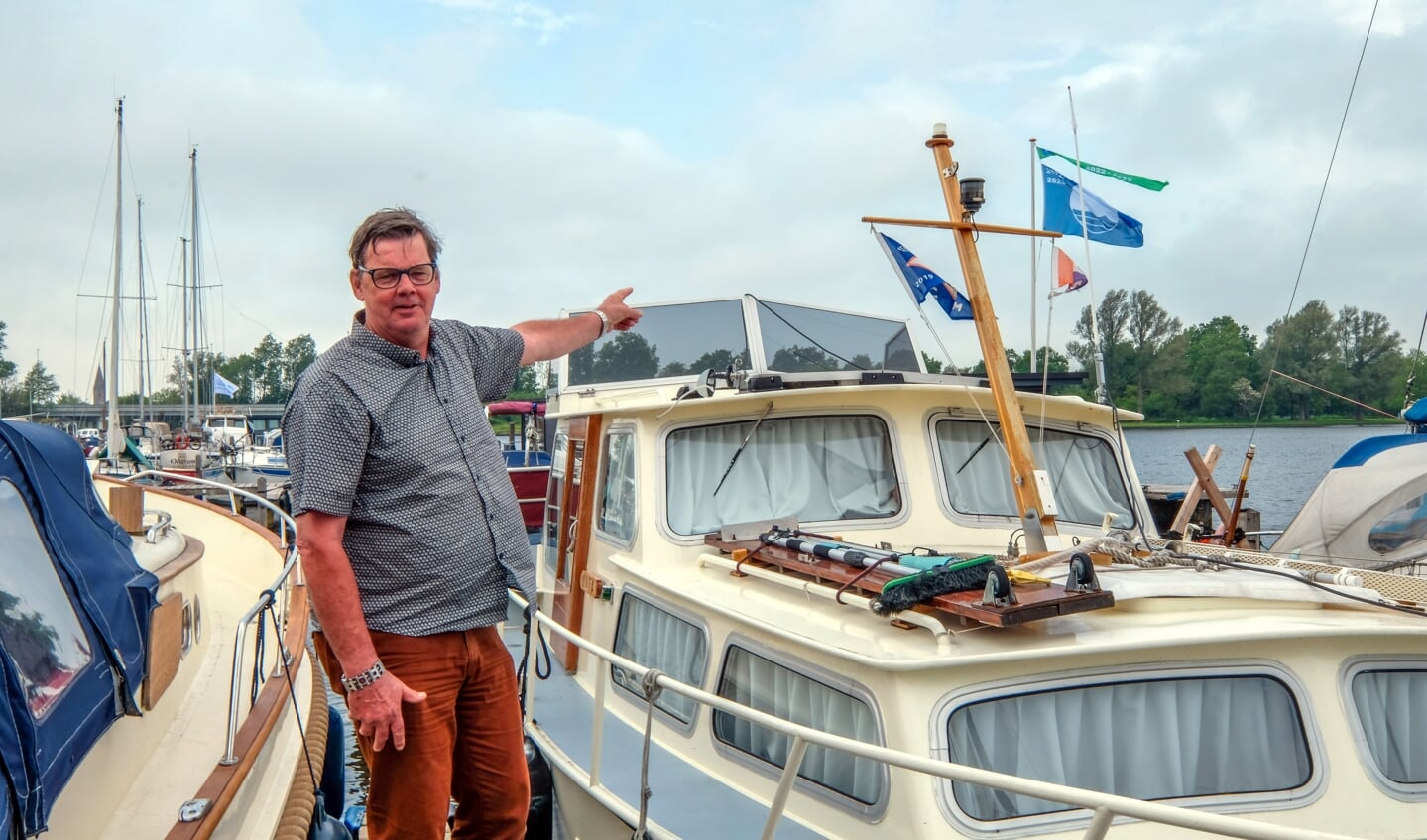 Menno Klein wijst naar de Blauwe Vlag en Groene Wimpel.