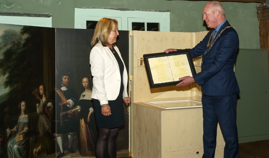 Burgemeester Eduard van Zuijlen neemt aankoopbewijs van Cornelis Valentijn in ontvangst van Jeannette Baas.
