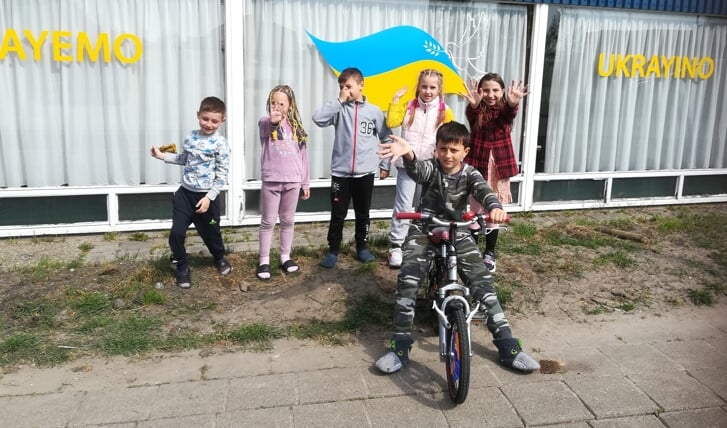 Oekraïense kinderen voor het gebouw in Woubrugge. Op de ramen staat de tekst 'Welkom Oekraïne'.