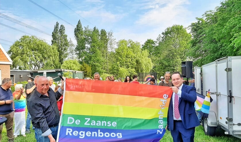 Frank Vos van de stichting De Zaanse Regenboog en burgemeester Polak presenteren de vlag. 