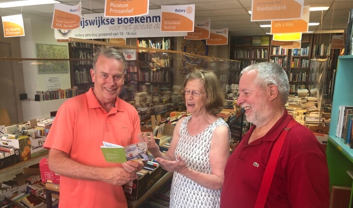 Liesbeth Kromhout overhandigt het vertaalboekje aan Peter Olierook (l) en Ger Bulder van de Rijswijkse Rotary in de boekenmarkt van de club. 