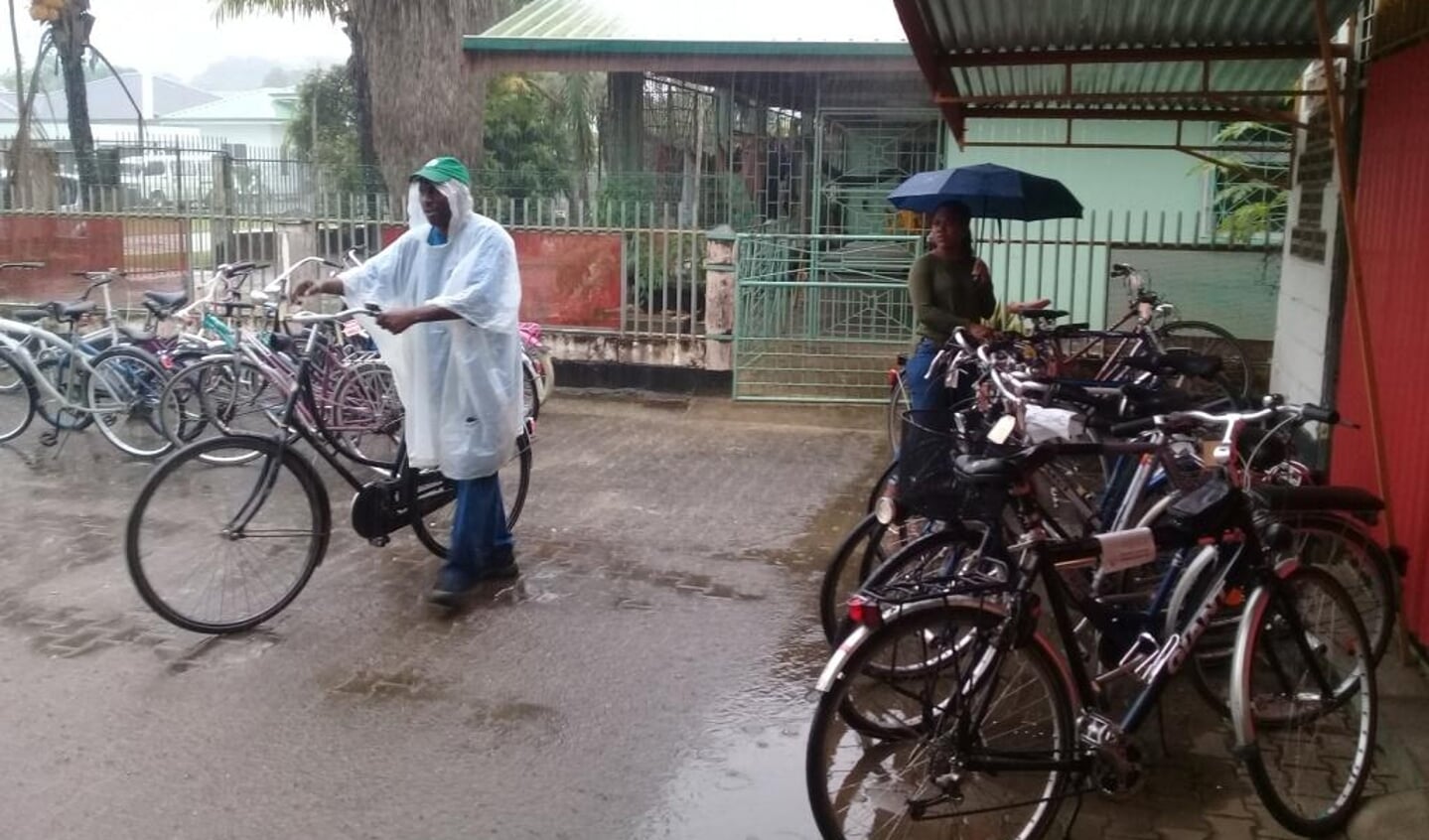 Medewerkers halen in de regen de fietsen binnen.