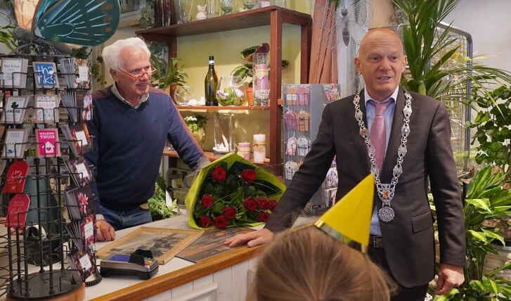 Burgemeester Bert Wijbenga met de bos rozen op de laatste verkoopdag dinsdag bij bloemist Jac. Verkuil.