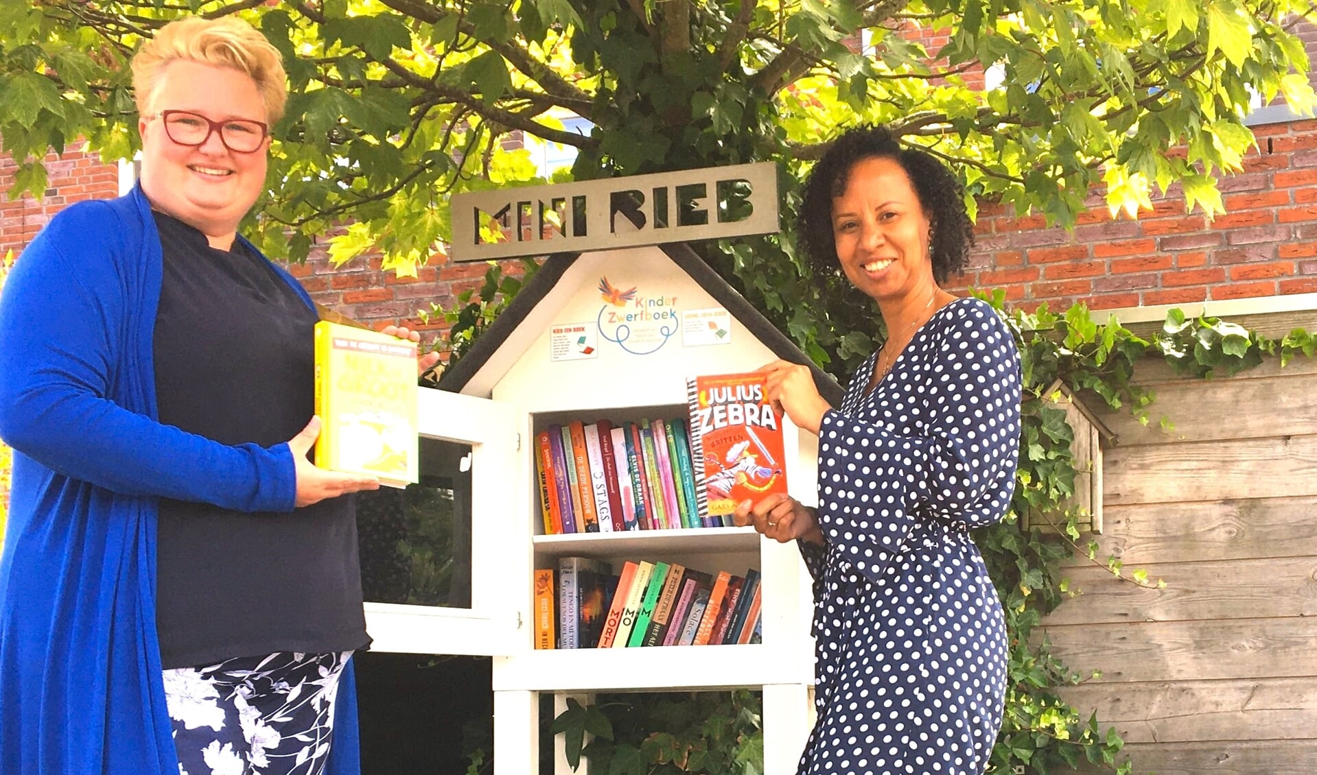 Rochelle (r) en Irene bij de minibieb met veel nieuwe kinderboeken.