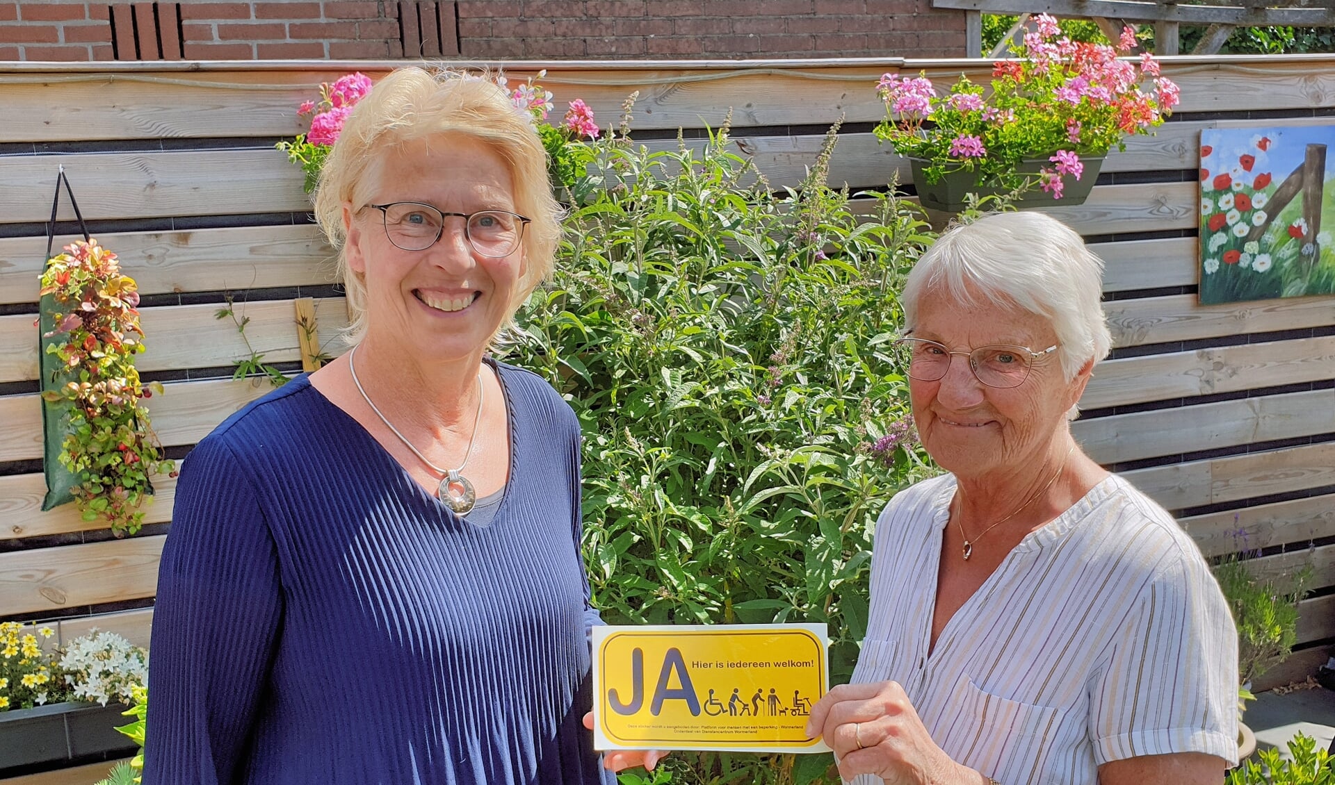 Voorzitter Monique van Zanten en secretaris Gurie Lelie-Rezée met de gele sticker die gelijk duidelijk maakt ‘Ja, hier (in deze winkel/ruimte) is iedereen welkom’.