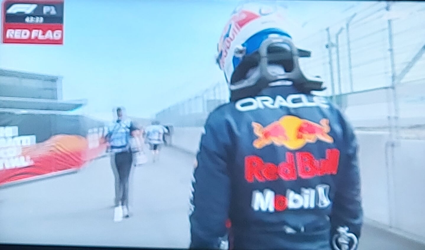 Max Verstappen loopt naar de pitbox nadat zijn auto ermee stopte.