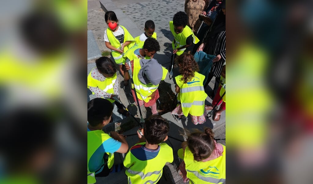 Kinderen en volwassenen van Wijkcentrum Dreesplein ruimen zwerfafval op.