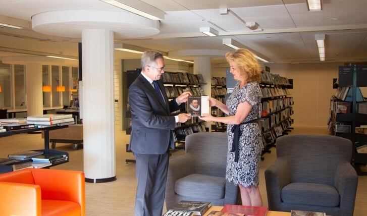 Burgemeester Jos Wienen overhandigt het boek aan directeur Roxane van Acker. 