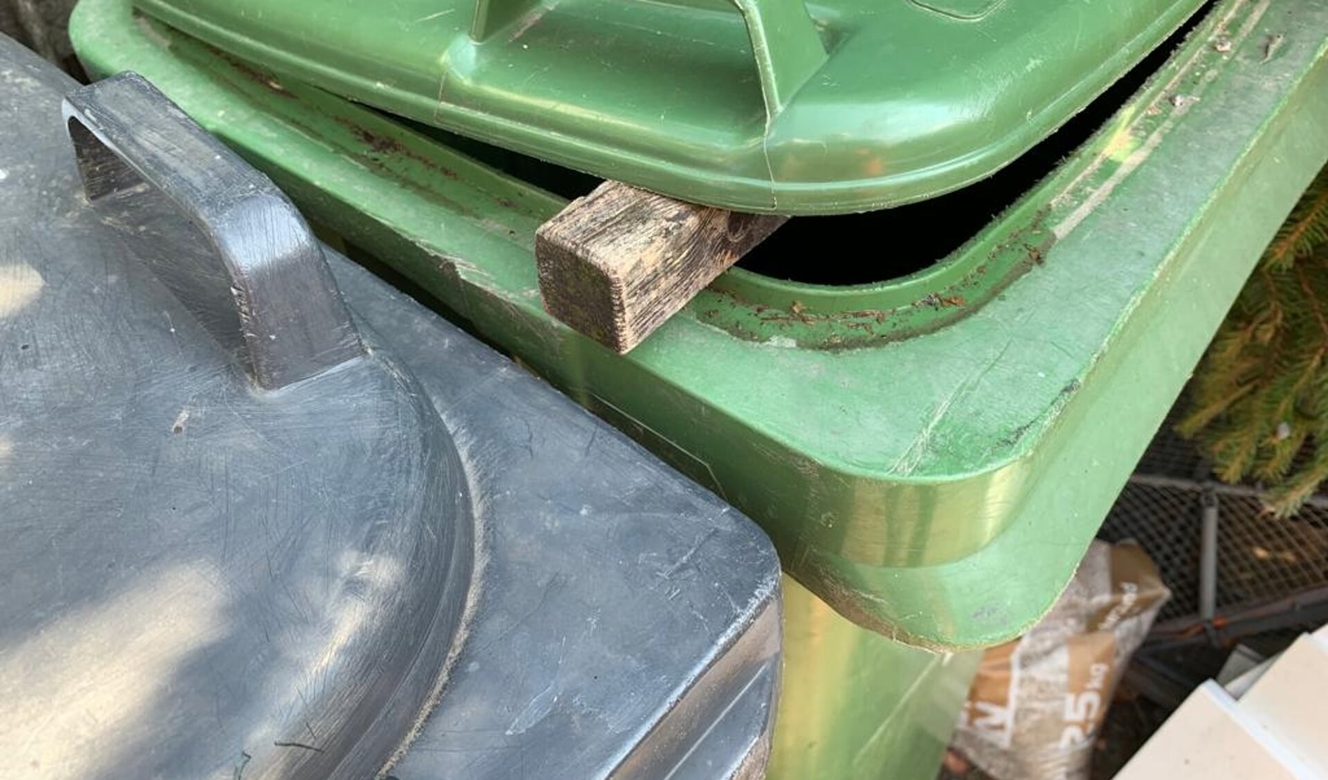 Leg een houten balkje tussen de klep van je afvalcontainer.