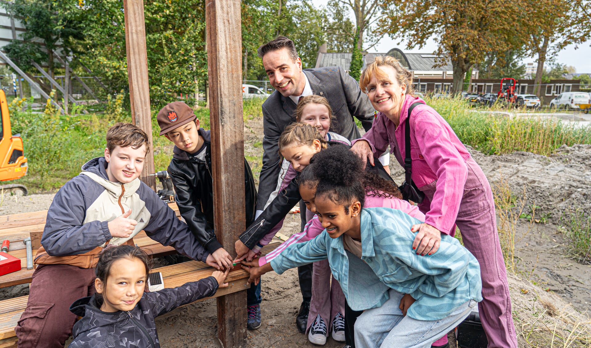 Wethouder Jasper Nieuwenhuizen en kunstenares Su Tomesen plaatsen samen met basisschoolkinderen de eerste steen.