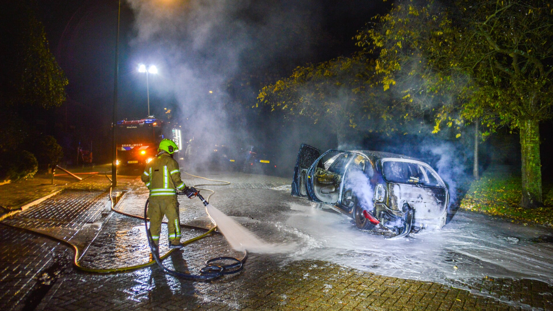 Brandweer blust de geparkeerde auto aan de Lijsterlaan in Maassluis