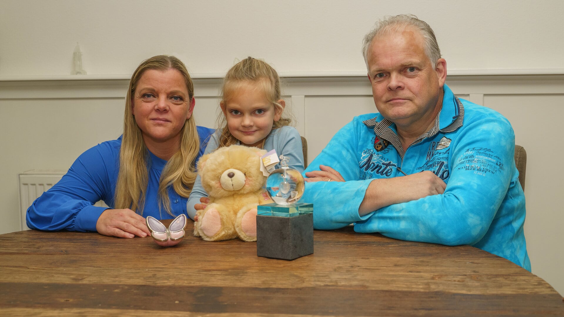 Marian en Louis met hun dochter Yesslin (6). Op tafel de vlinder, de glazen en bol en de beer die symbool staan voor het verlies van Jacey.