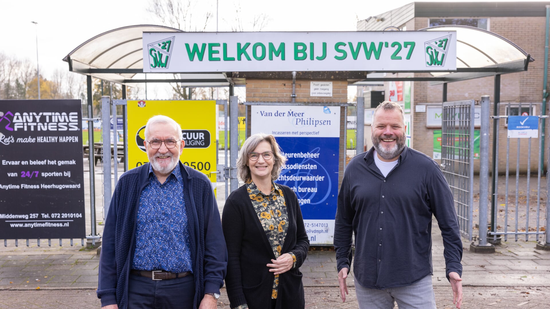 Hans Kuipers (l), Martine Raams en Jeroen Appelman voor de ingang van het terrein van SVW '27. De tekst boven de toegangspoort spreekt boekdelen.