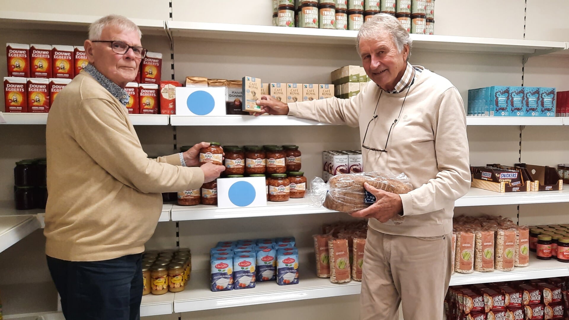 Leo van Houwelingen(links) en Karel van der Poel van de Vlaardingse voedselbank, staan voor de volle schappen met voedselproducten.