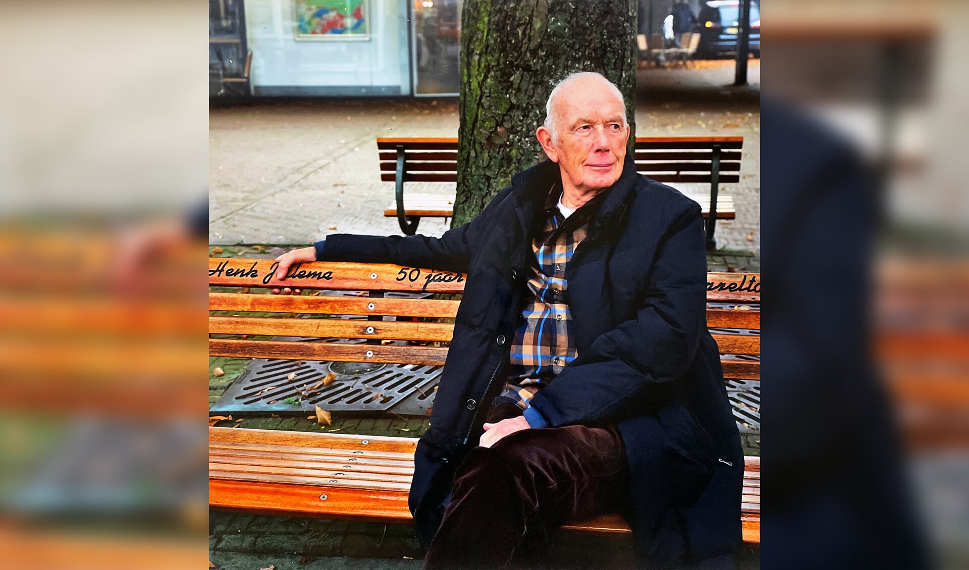Henk Jellema (1 juni 1935-21 november 2023) op het bankje voor hem, op het Plein in Bergen