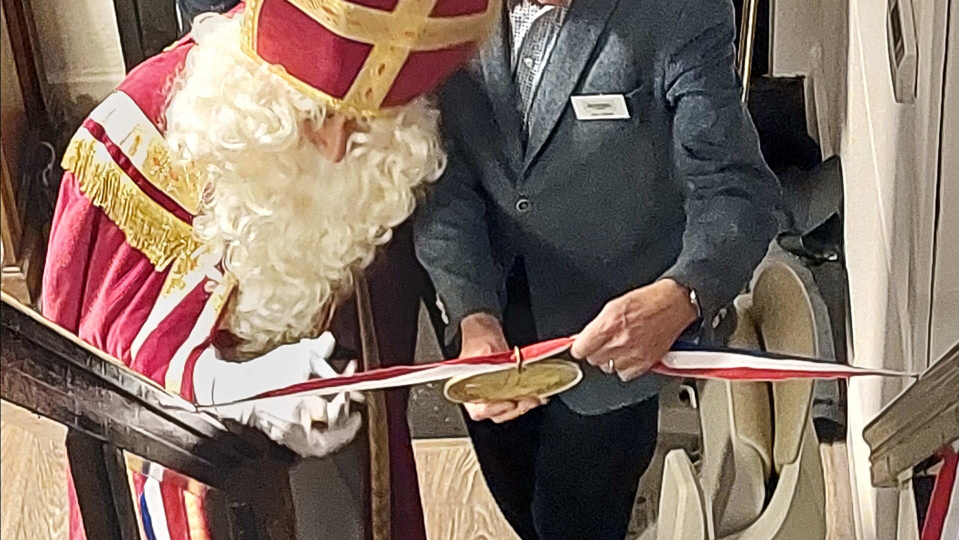 Met een voor een oudere man verrassend vaste hand knipte Sinterklaas een lint met daaraan een gouden medaille door.