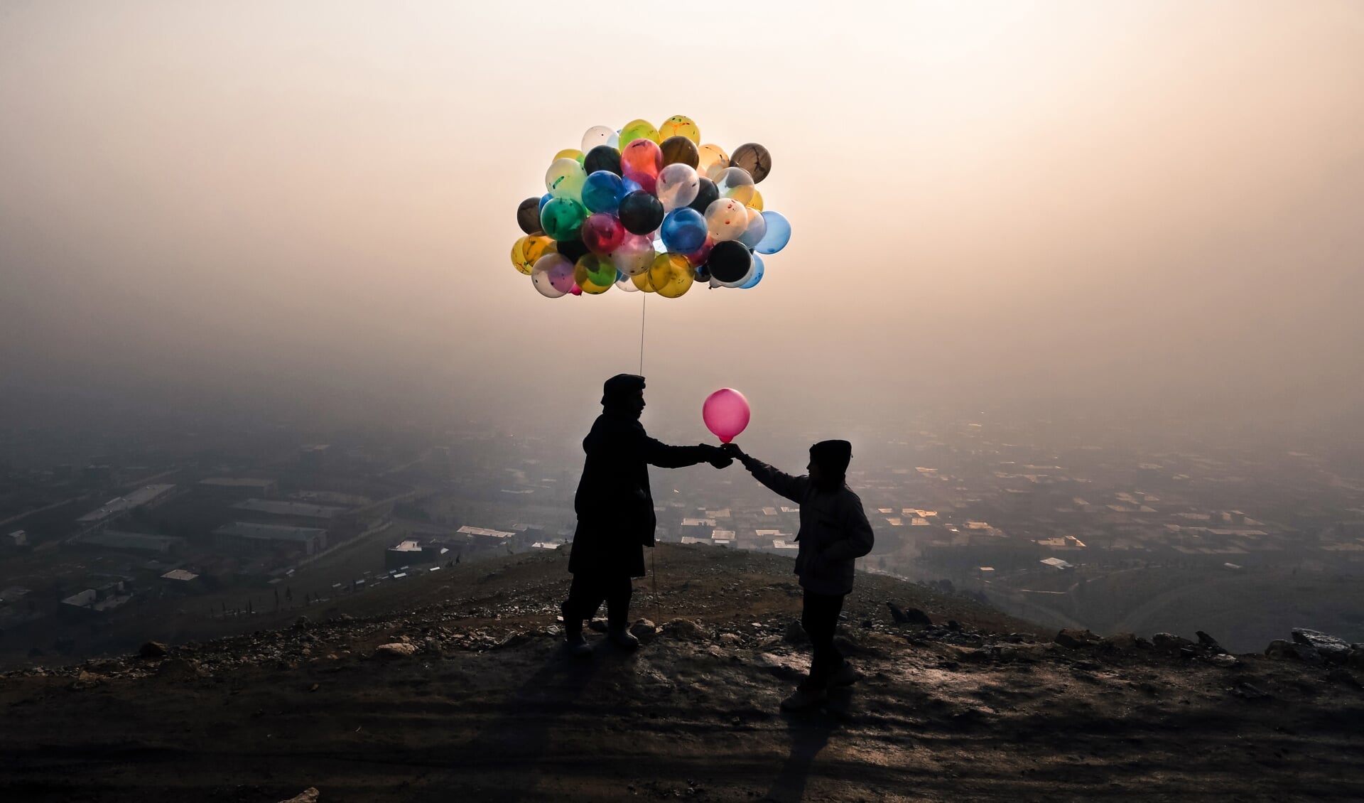 Een Afghaanse man verkoopt op donderdag 10 december 2020 een ballon op een heuveltop in een buitenwijk van Kaboel.