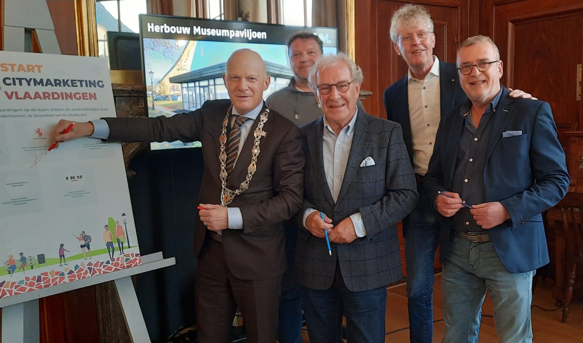Gerrit van Toor, kijkt met een blij gezicht staande naast burgemeester Bert Wijbenga, hoe het Citymarketingplan met een handtekening wordt bekrachtig. Op de achtergrond kijken v.l.n.r mee Hewi Hoogendijk, Dirk Jan van de Weerdt en Hans van Beek.