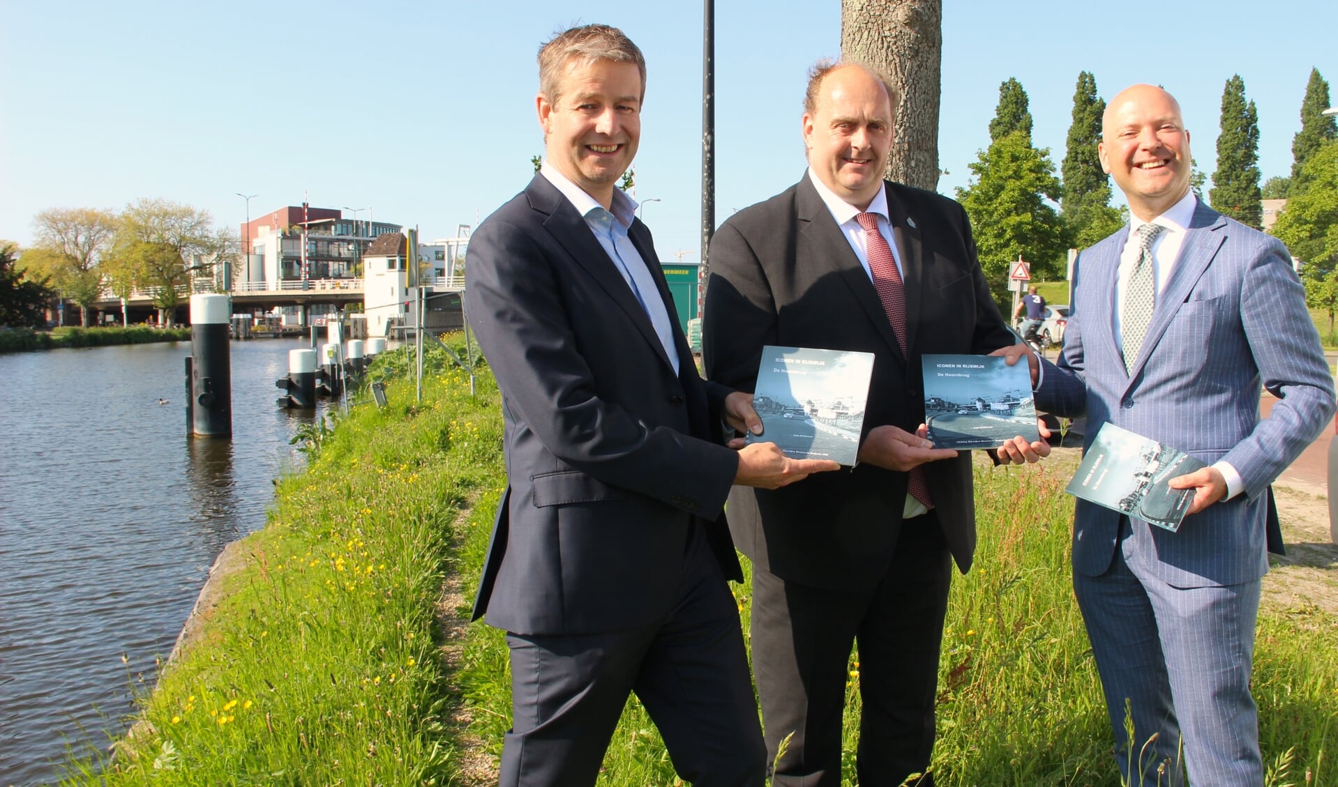 Wethouder Armand van de Laar(r) geeft het boek '850 jaar Hoornbrug' aan Frederik Zevenbergen(m) en Bert Jan Hemmen(l).