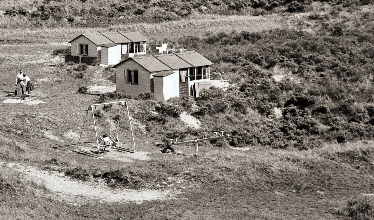 Foto begin jaren vijftig met twee van de vier Duyvishuisjes. Twee bewoners staan bij de waterpomp.
