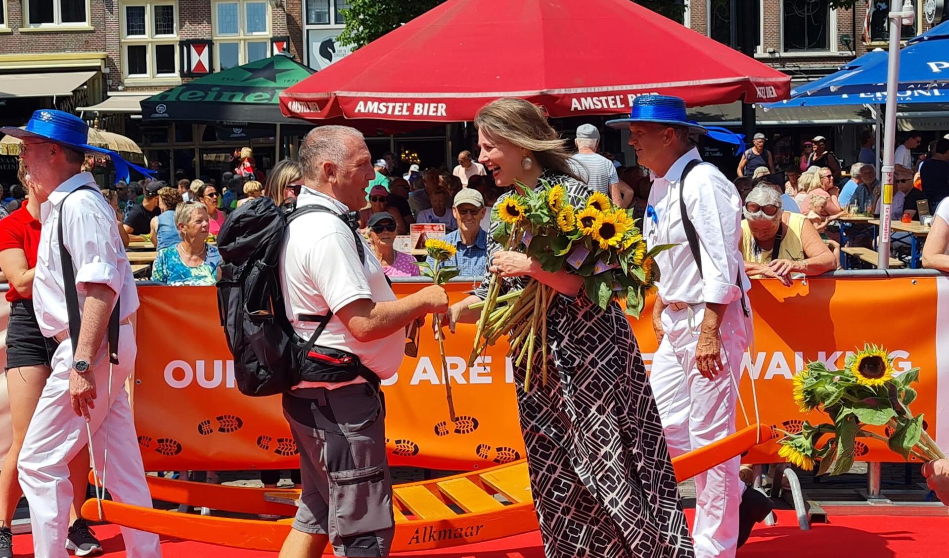 De Alkmaarse burgemeester Anja Schouten deelt zonnebloemen uit aan de wandelaars.