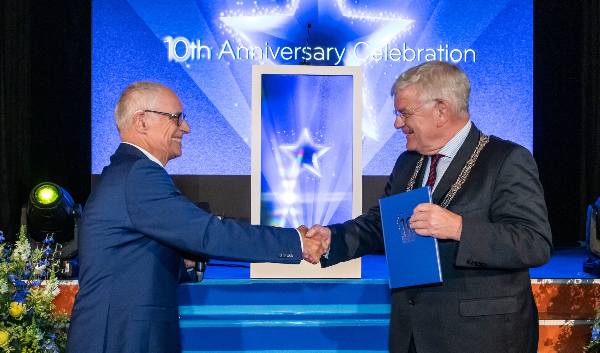Burgemeester Jan van Zanen ontvangt het eerste exemplaar van het jubileumboek.