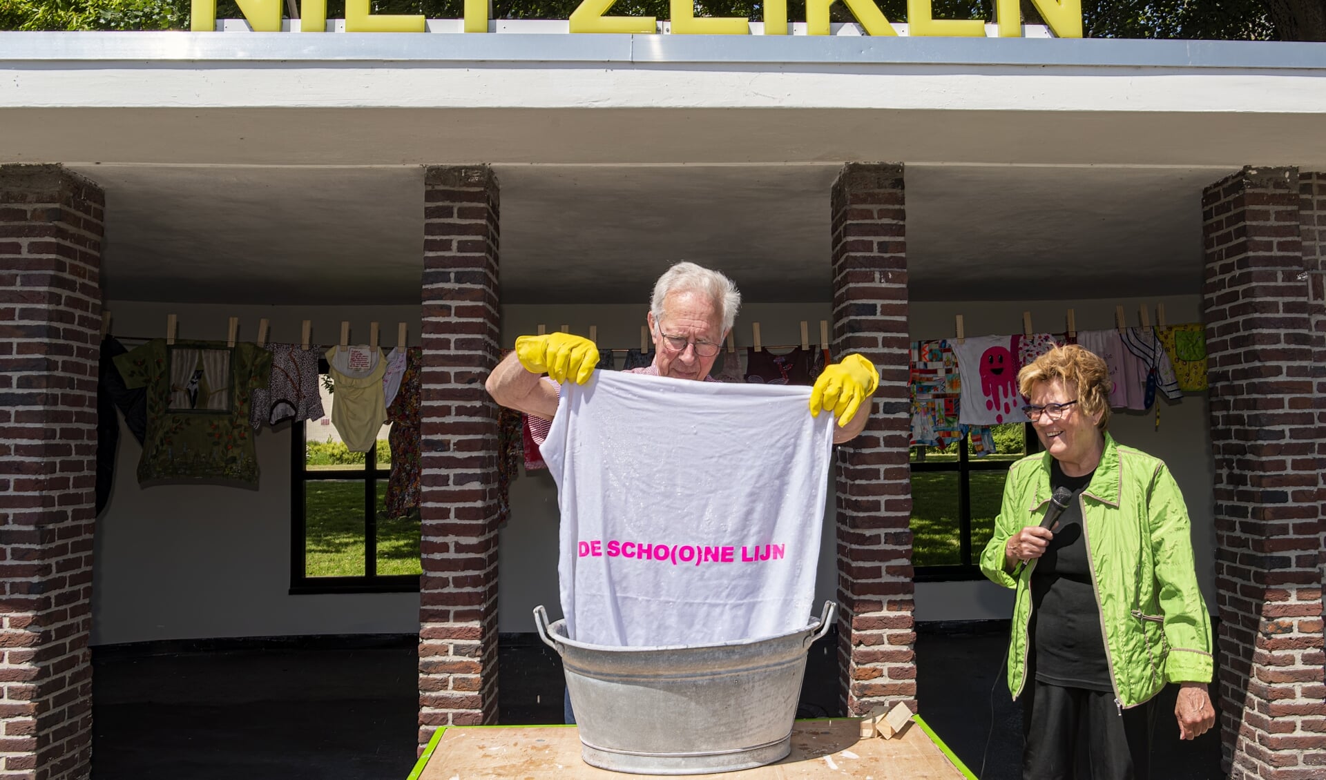 Oud-bugemeester Reinier Scheeres doet onder toeziend oog van Yvon Koopman de handwas in een zinken teil.