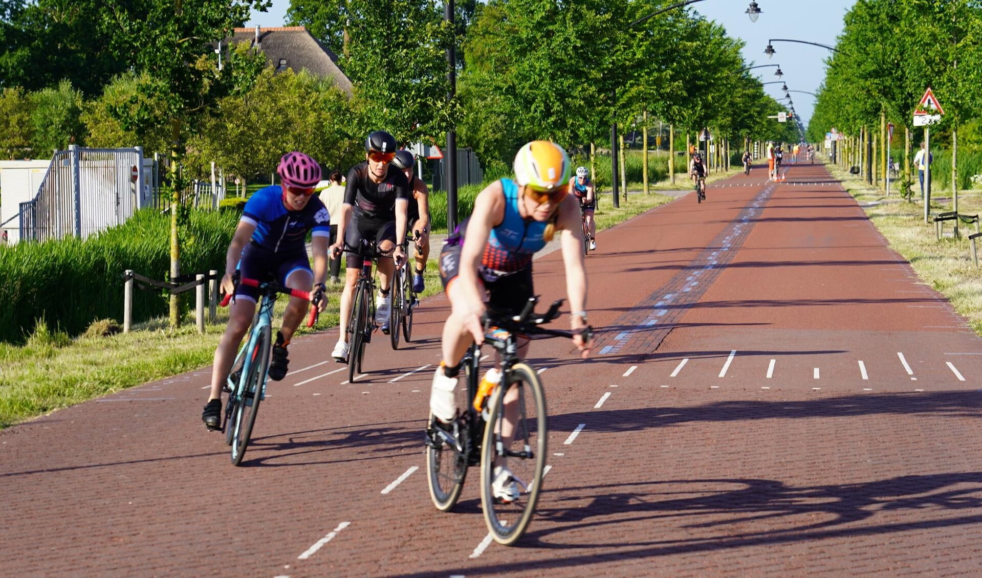 Deelnemers fietsen over de Middenweg. De wedstrijd werd vroegtijdig stilgelegd.