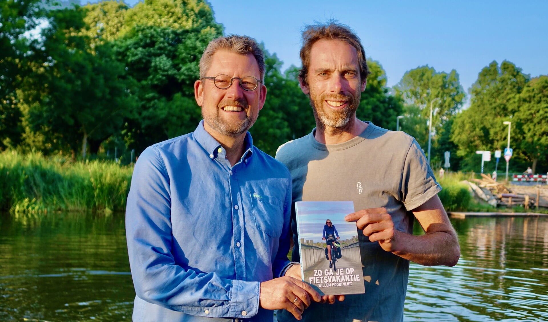 Willem Poortvliet (l) overhandigt het eerste exemplaar van zijn boek over fietsvakanties aan voormalig Tourrenner Laurens ten Dam.