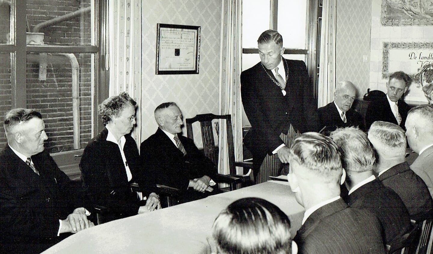 Burgemeester Loggers spreekt Cees Mol toe in 1953 bij zijn afscheid als gemeentesecretaris van Wor­mer. Op de foto links oud-wethouder Kenter, de vrouw van Mol en naast Loggers de ambtenaren ter secretarie J. Molenaar en P. Boll. Op de rug gezien een aantal raadsleden.