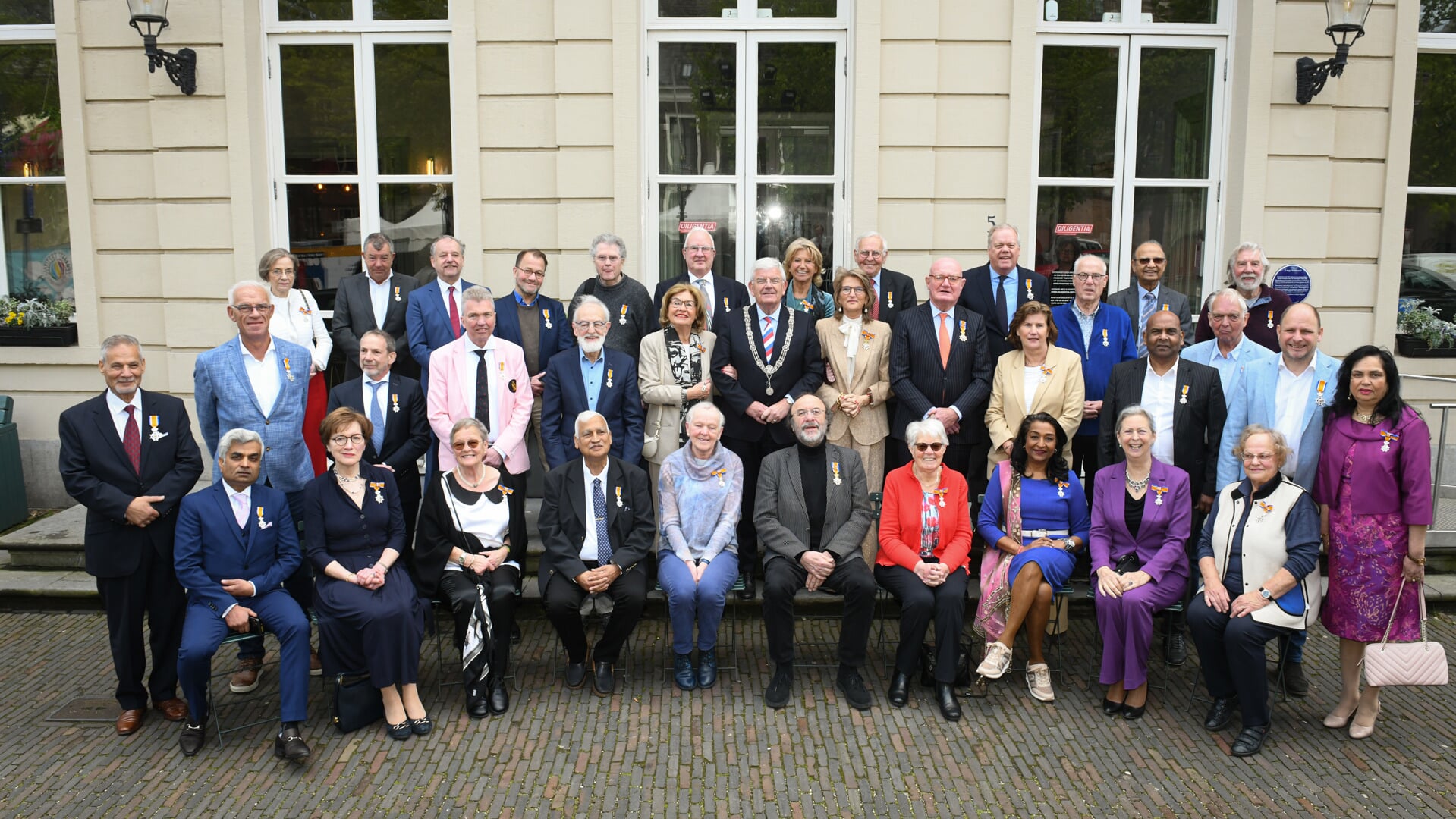 De burgemeester Jan van Zanen gaat samen met de gedecoreerden voor theater Diligentia op de foto.