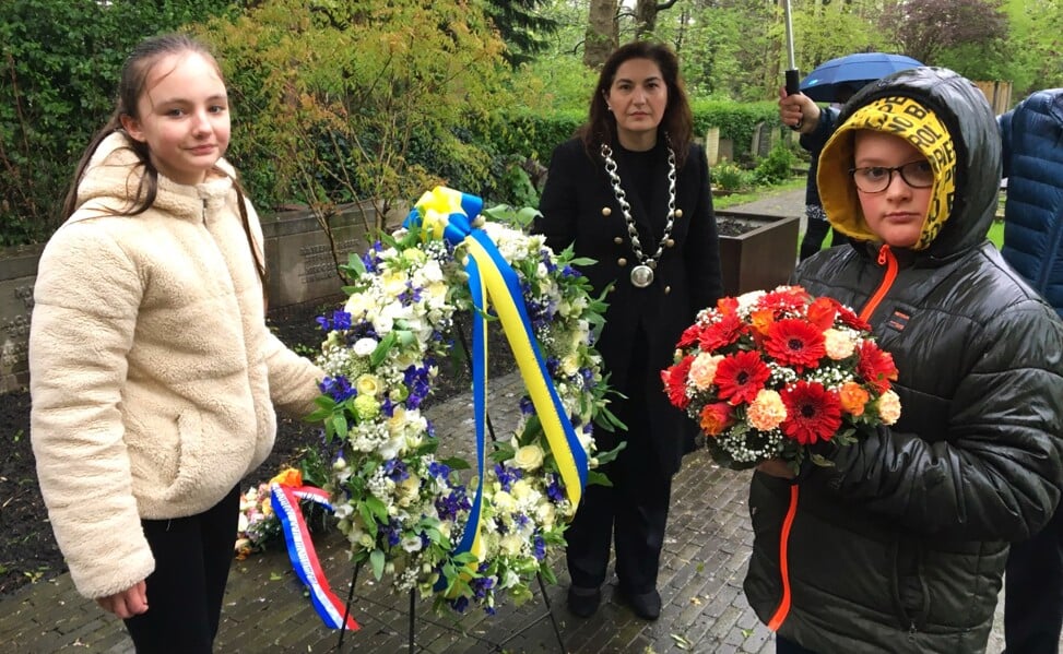 Burgemeester Huri Sahin en enkele leerlingen van de Godfried Bomansschool plaatsen bloemen bij het monument voor de Slag om Ypenburg.