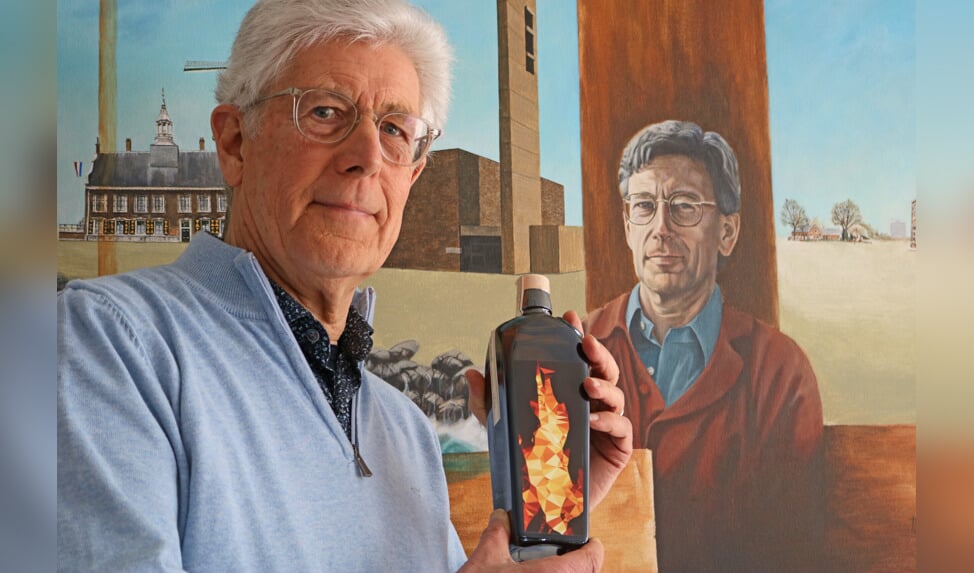 Theo van Giezen tegen de achtergrond van een portretschilderij van Jeffrey Burger. Hij houdt de Vriendenfles van 2023 (Aldo Hoeben) in de hand.