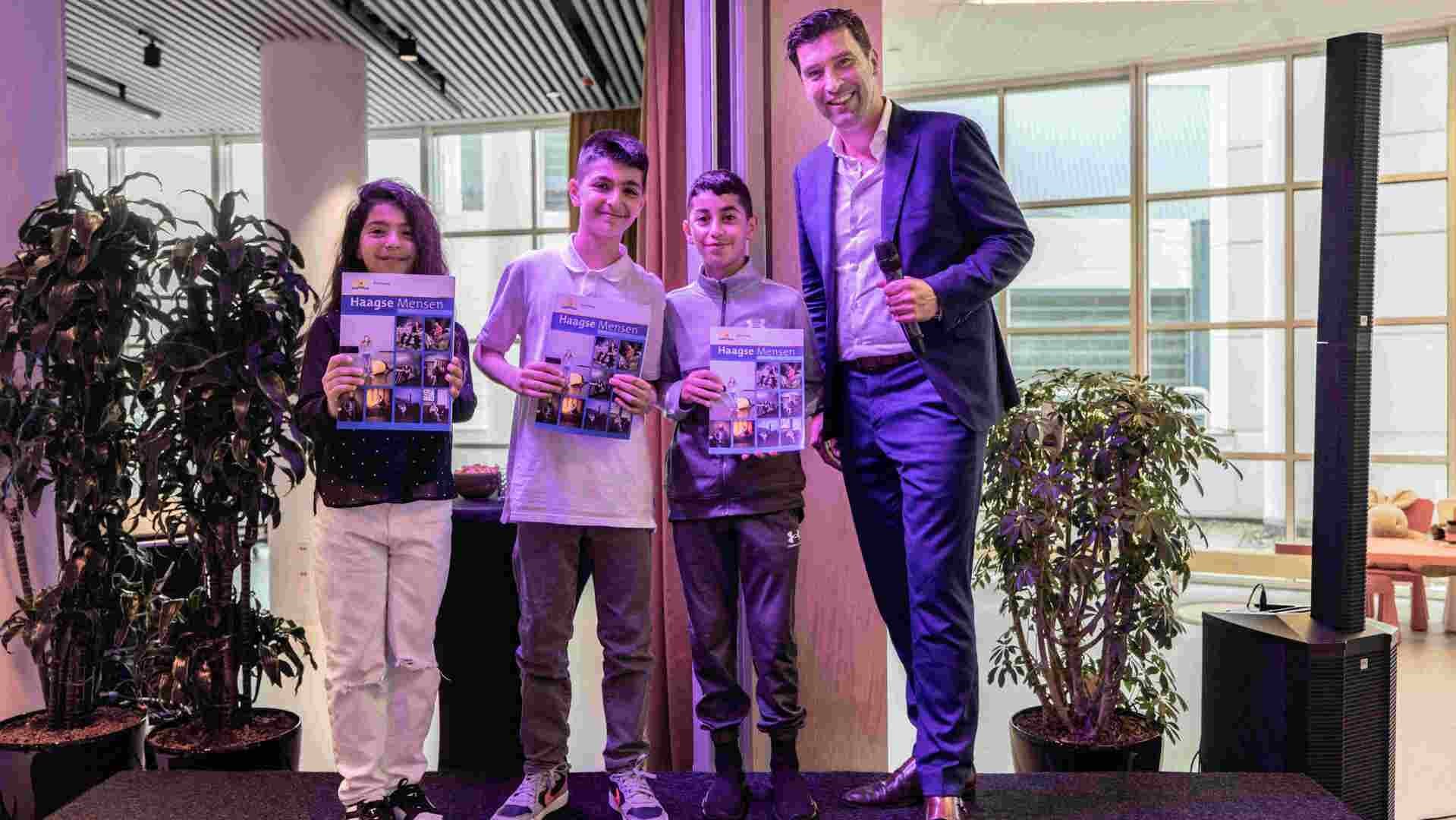 Kinderen tonen trots het magazine waarin ze over hun favoriete plek in Den Haag vertellen. 